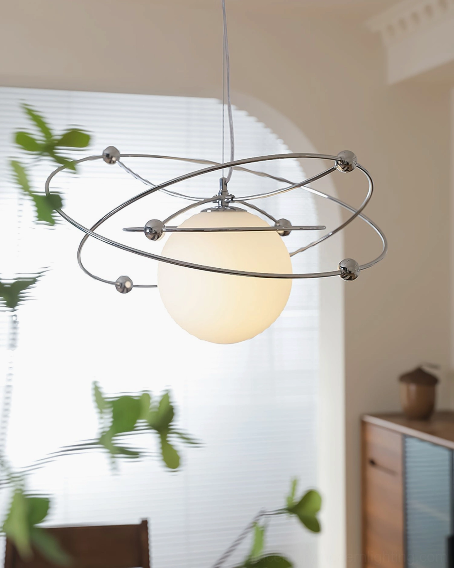 Overhead view of orbital pendant lamp in warm dining room with green plants and boho styling