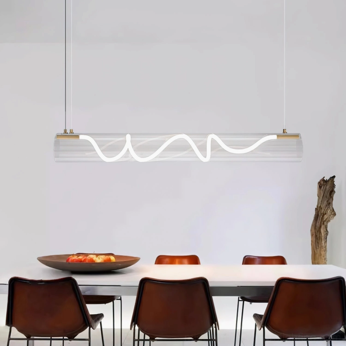 Attalea linear pendant chandelier side view in minimalist dining room with long table, showcasing brass end caps and wavy LED design