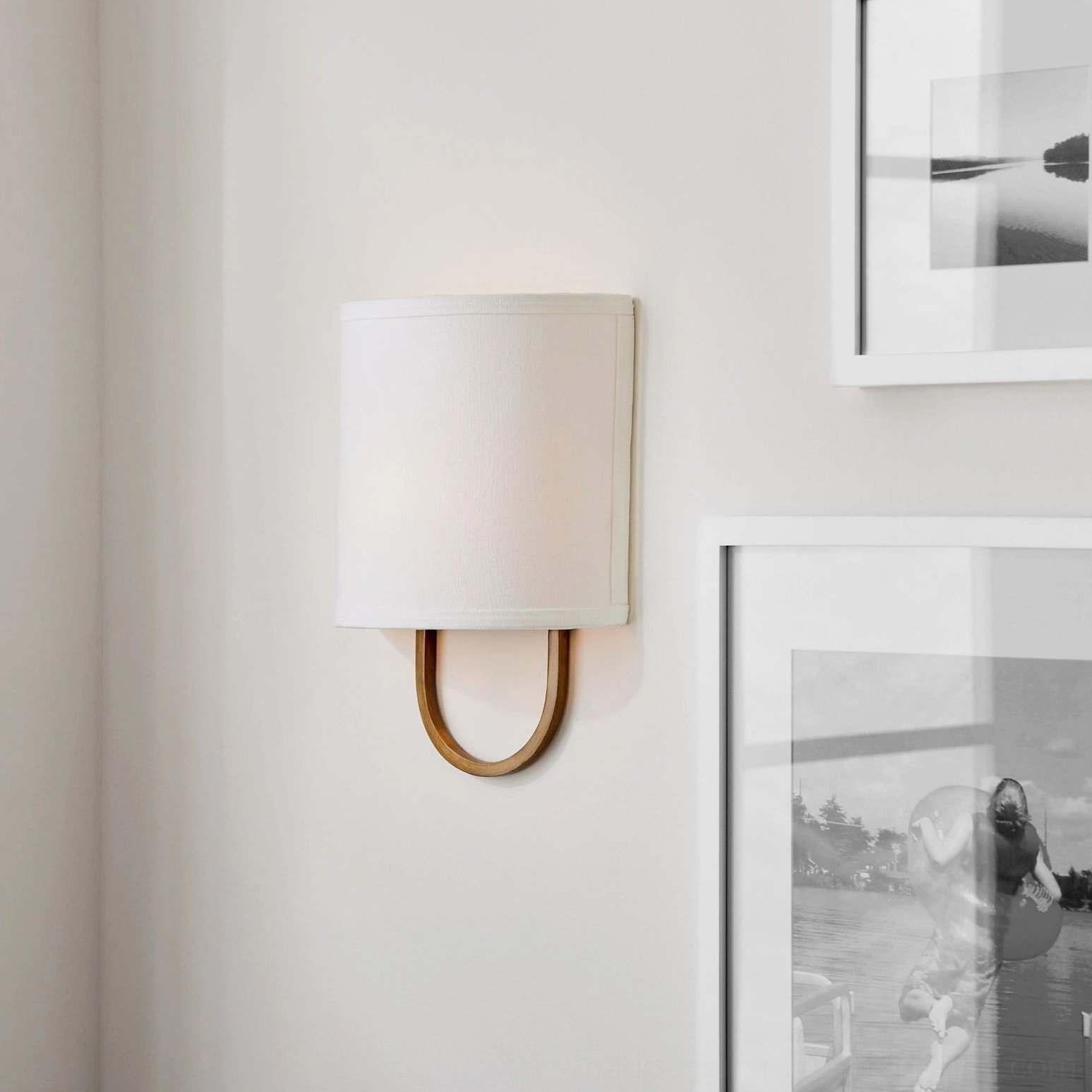Brass Atticus wall lamp with square off-white fabric shade on gallery wall, architectural lighting detail