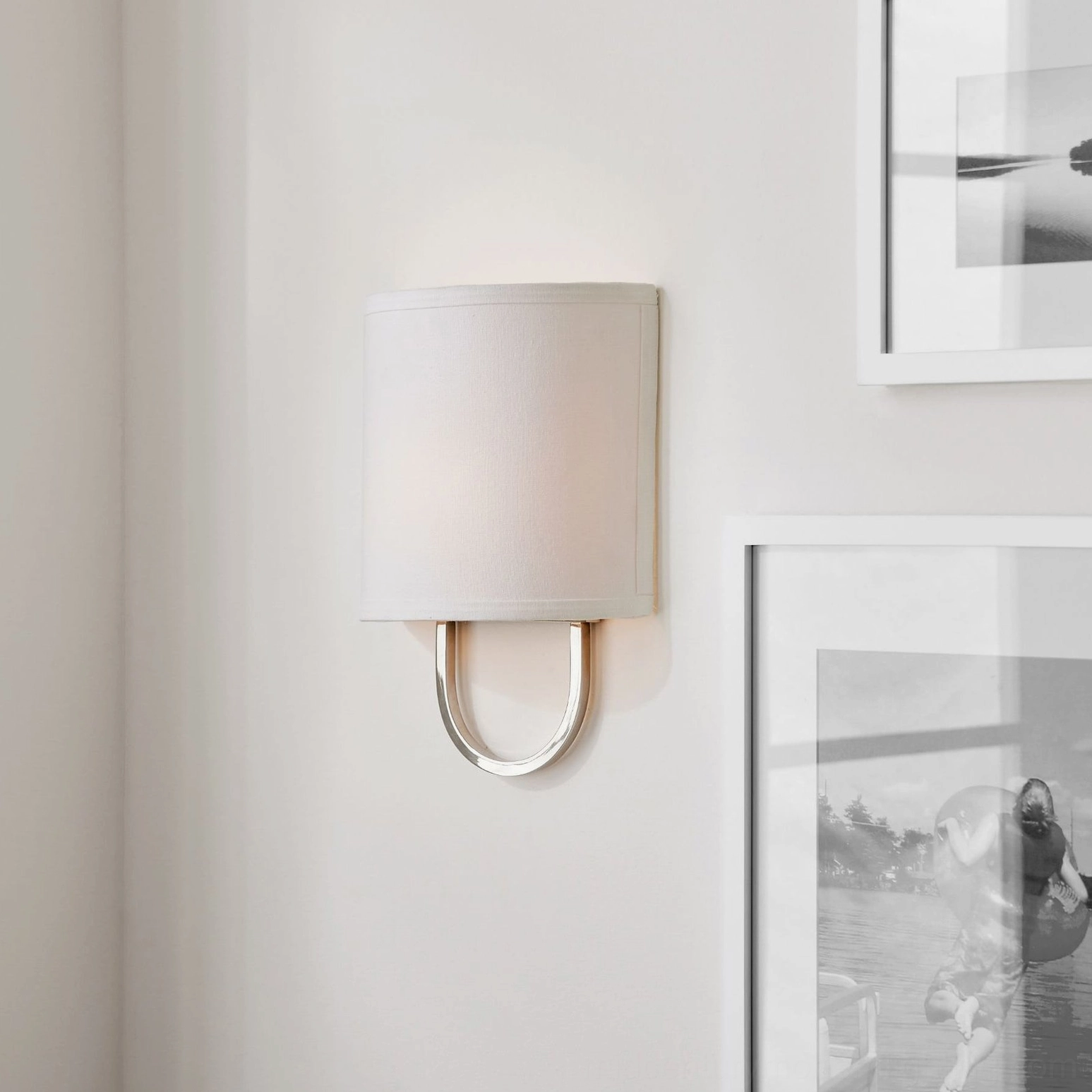 Atticus mid-century wall sconce with polished silver nickel bracket and off-white fabric shade, gallery wall detail