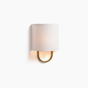 Atticus mid-century modern wall sconce with brass U-shaped bracket and off-white fabric drum shade, frontal close-up view