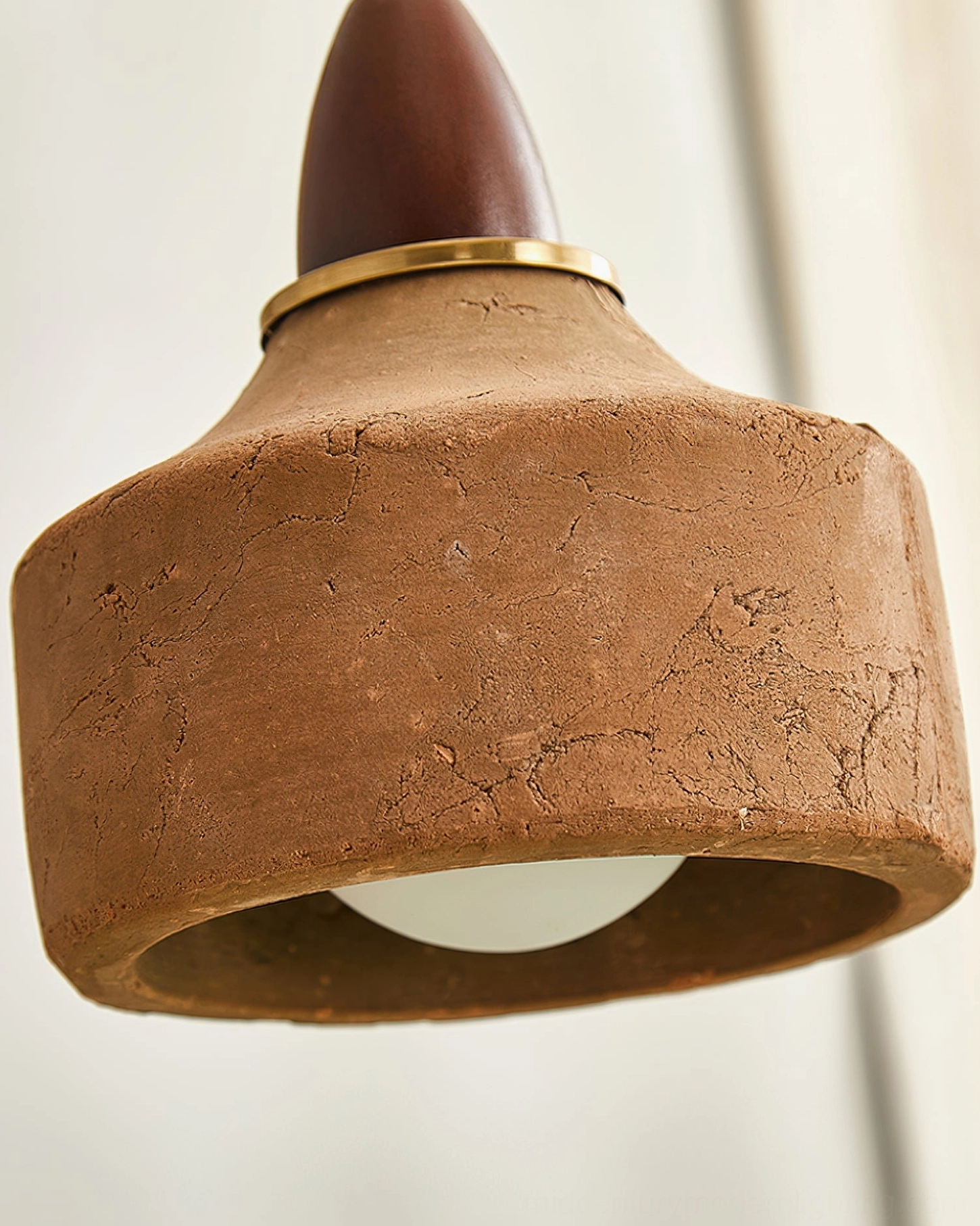 Extreme close-up detail of Auburn pendant's textured ceramic surface, rough matte finish and metal accents