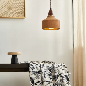 Warm terracotta ceramic pendant light hanging above entryway console table, three-quarter perspective