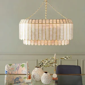 Two-tier capiz shell chandelier illuminated in formal neoclassical dining room above elegant table setting, warm ambient lighting, coastal glam style