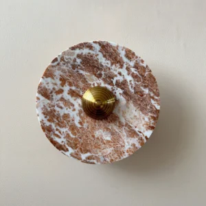 Close-up detail of Aurora wall lamp showing natural red marble texture and brown-white veining pattern