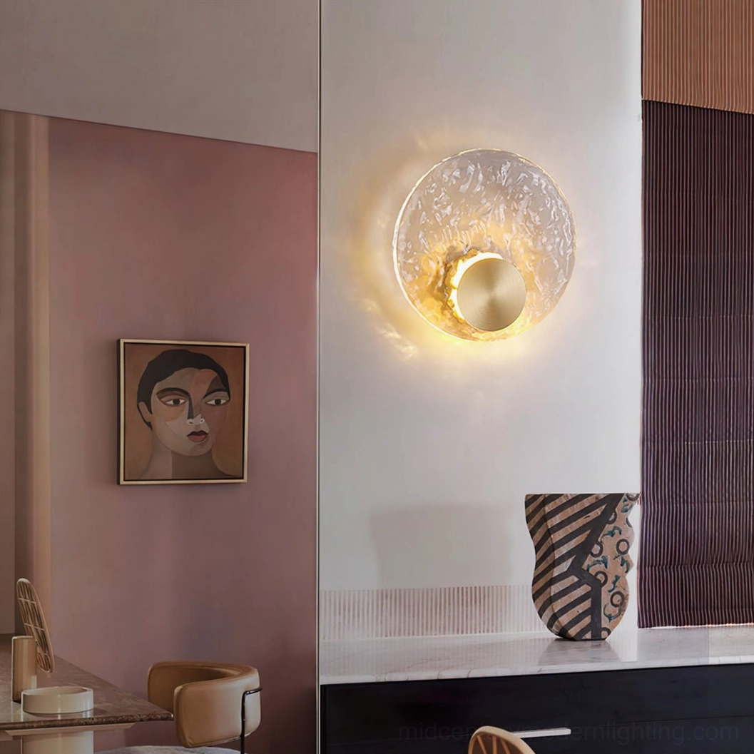 Circular brass wall sconce in vanity and dining area with pink accent wall and portrait artwork, contemporary luminaire