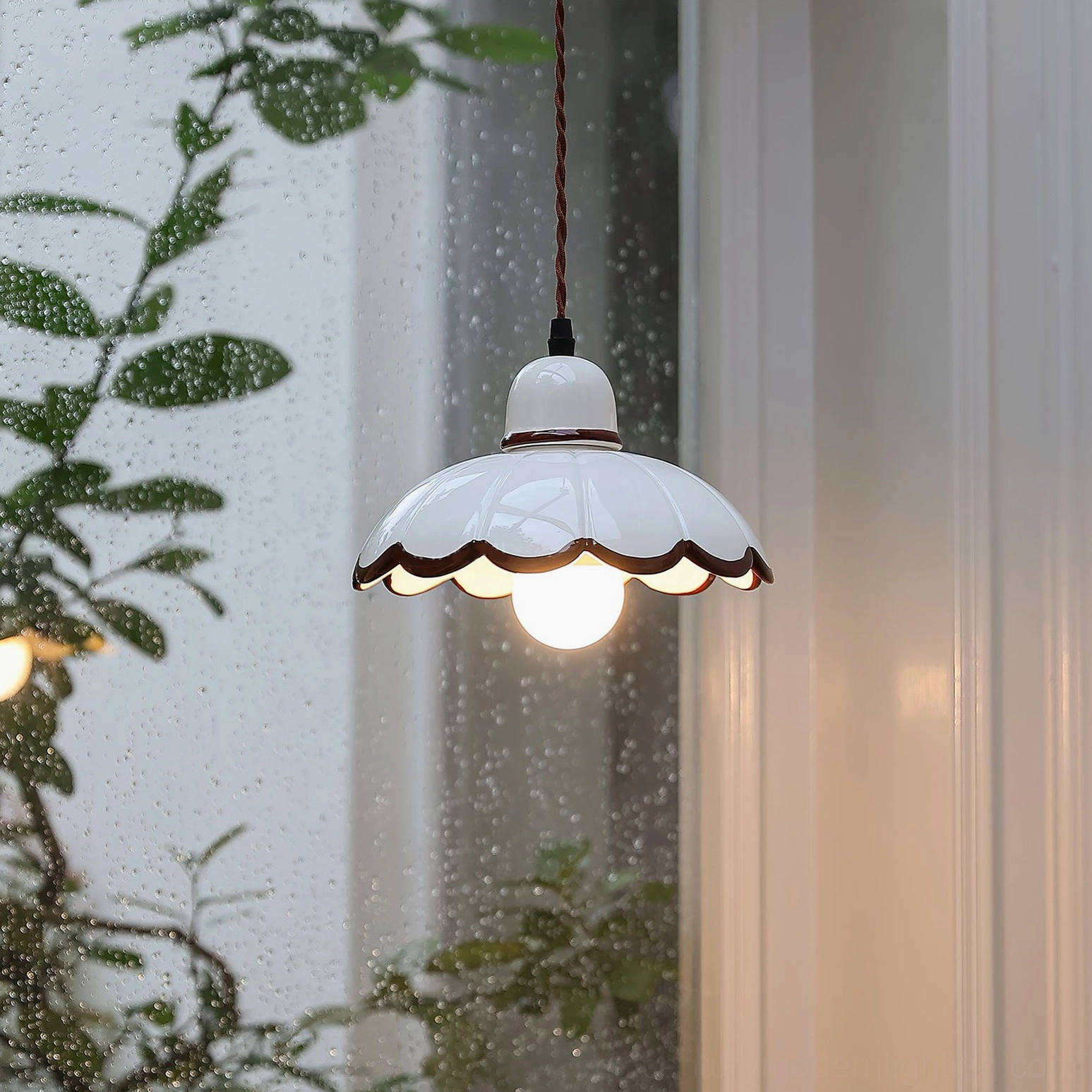 Avalon pendant light glowing indoors with exposed Edison bulb, side view near window