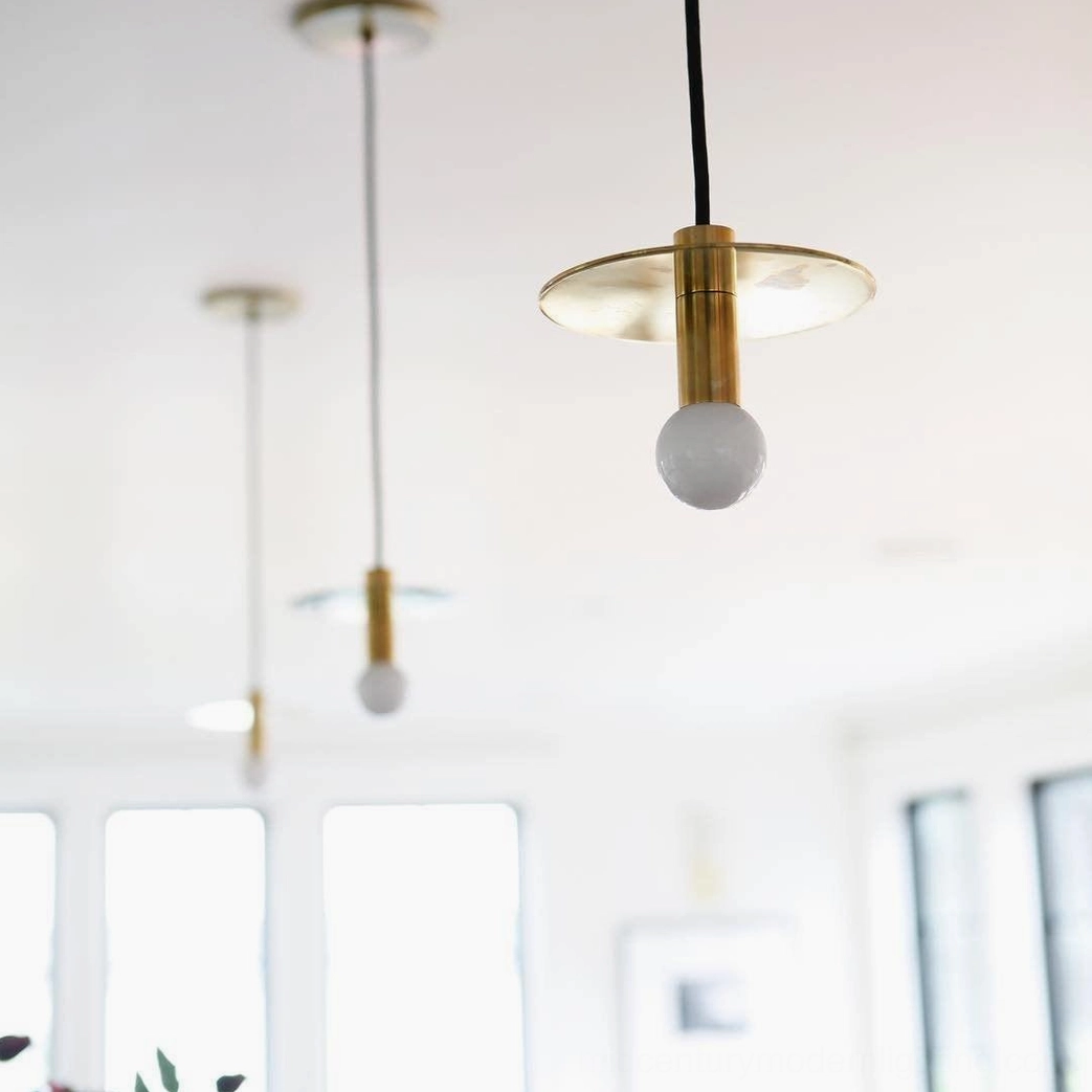 Multiple Avida minimalist pendant lights with brass gold finish hanging at varying heights in contemporary residential room