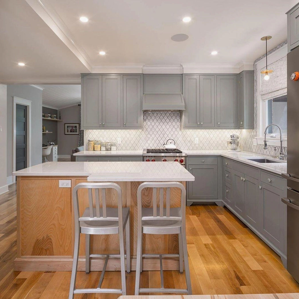 Avida brass disc pendant lights installed above modern kitchen island with grey cabinetry and wood flooring