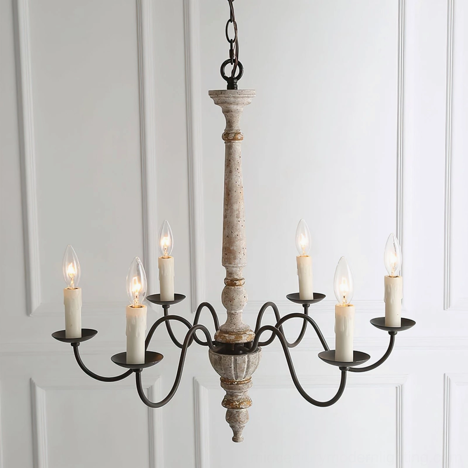Close-up detail of Avignon farmhouse chandelier with weathered white turned wood post and black scroll metal arms against white paneled wall