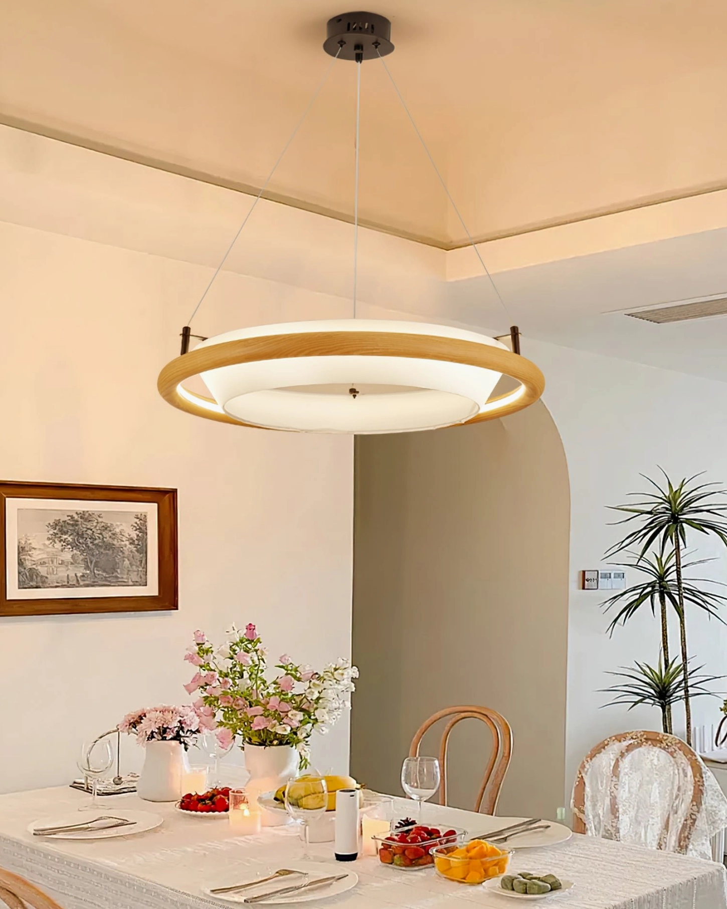 Azria wood chandelier with light wood finish - eye-level view in Scandinavian-inspired dining room with natural wood frame