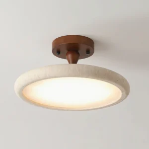 Close-up detail of Bailey ceiling light - warm LED glow illuminating textured travertine stone surface