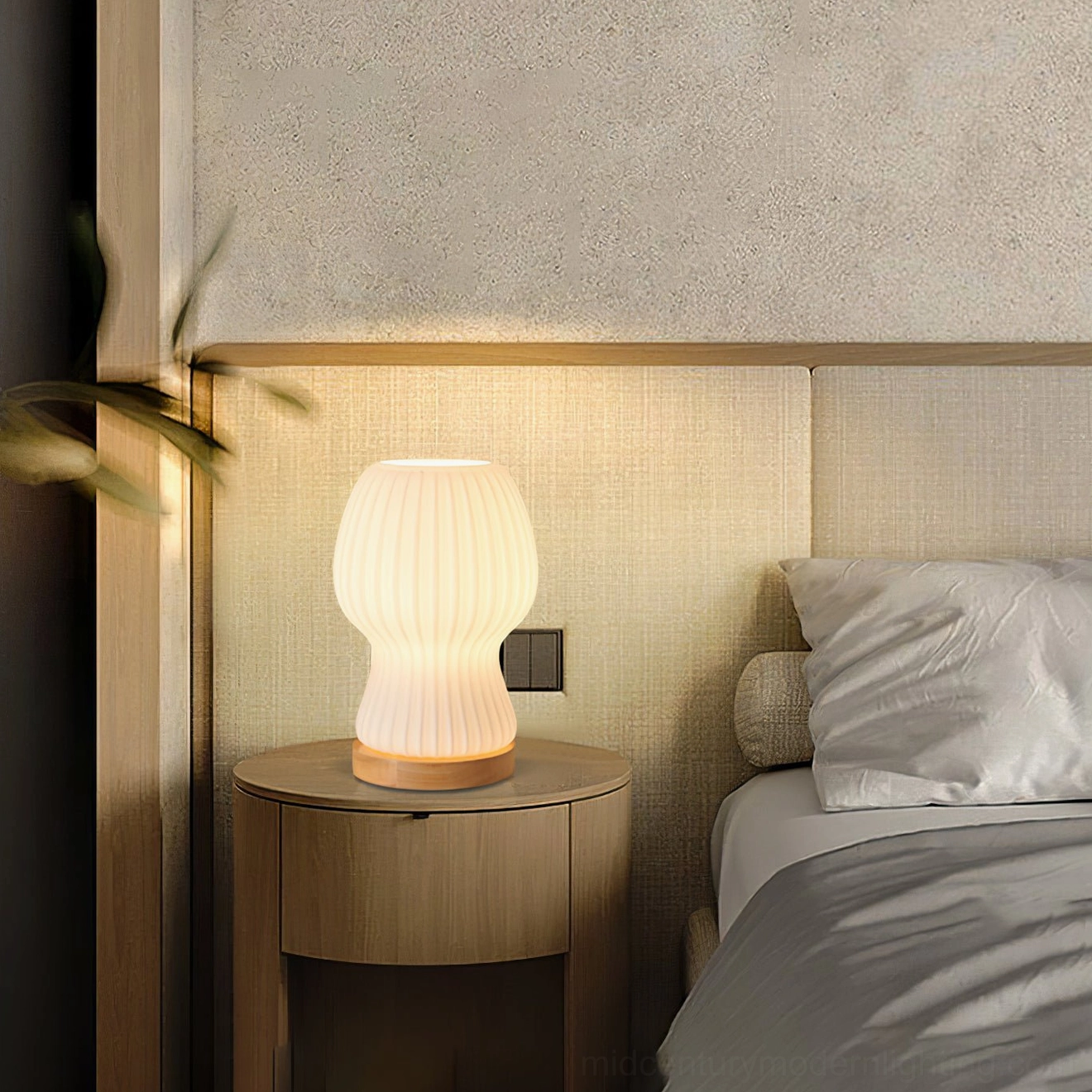 Baja table lamp on compact bedside nightstand with wall power socket visible