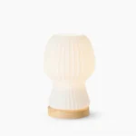 Baja pleated glass table lamp with natural wood base on white background, modern mid-century design