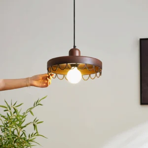 Dark walnut Balton wooden pendant light with warm glowing bulb, hand touching lamp, indoor botanical setting