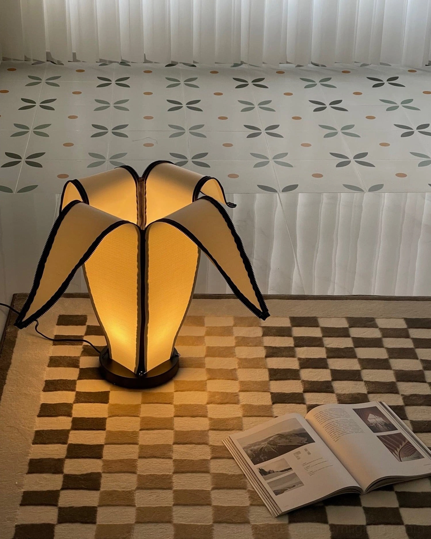 Warm glowing banana table lamp beside bed on cozy rug with patterned textile decoration