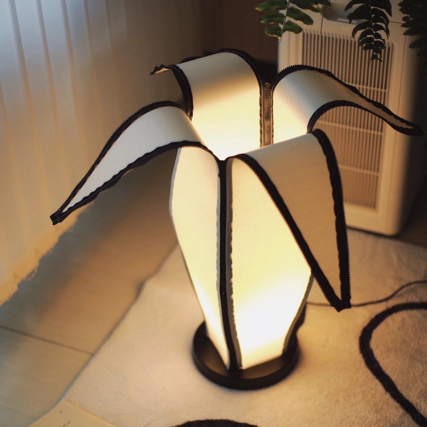 Close-up side view of banana table lamp showing fabric shade with black stitching trims detail