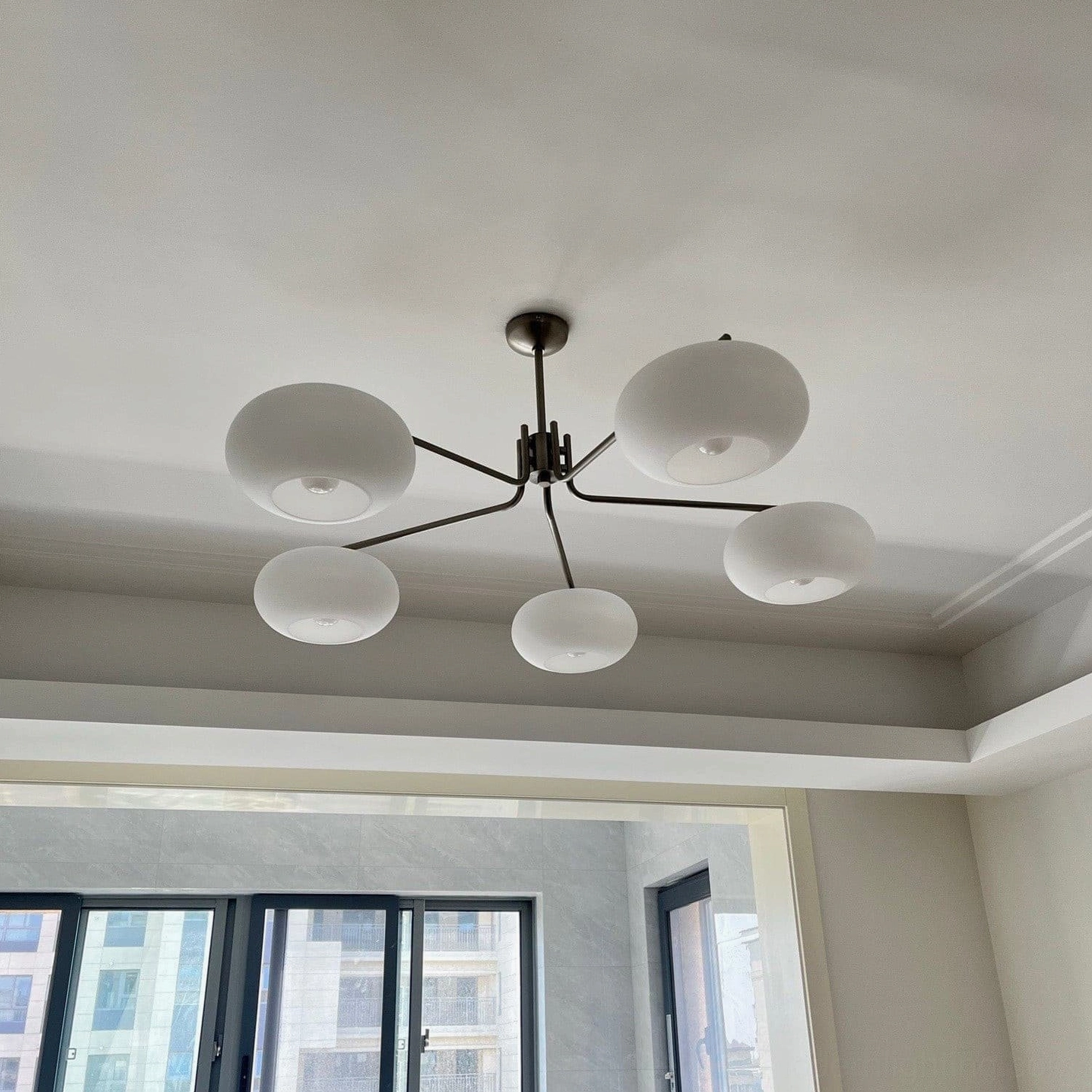 Barndon 6-head oversized frosted glass chandelier in modern living room with floor-to-ceiling windows, matte black metal frame