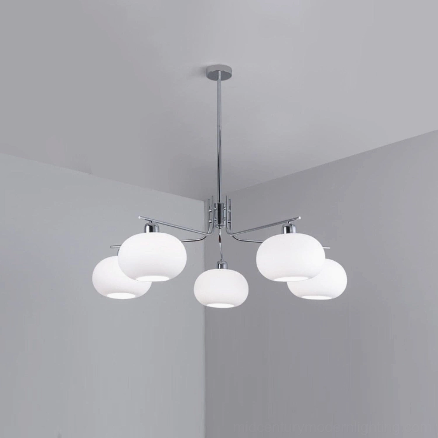 Barndon industrial chandelier installed in minimalist apartment corner, showing warm ambient lighting effect with chrome metal finish
