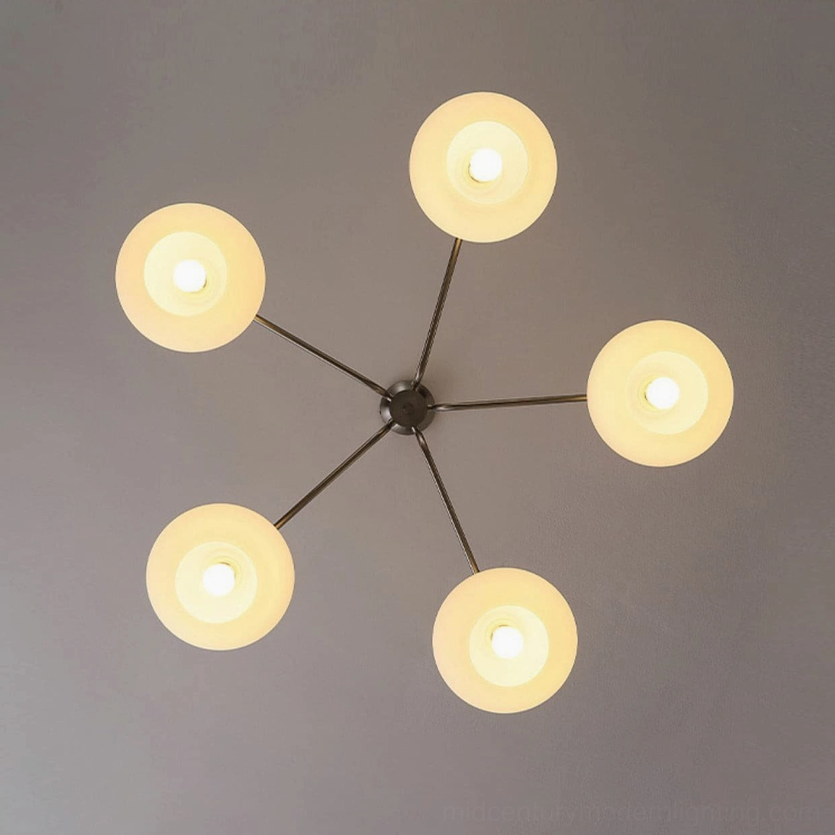 Barndon sputnik style mid-century modern chandelier top view on gray background, radial metal frame with warm yellow frosted shades
