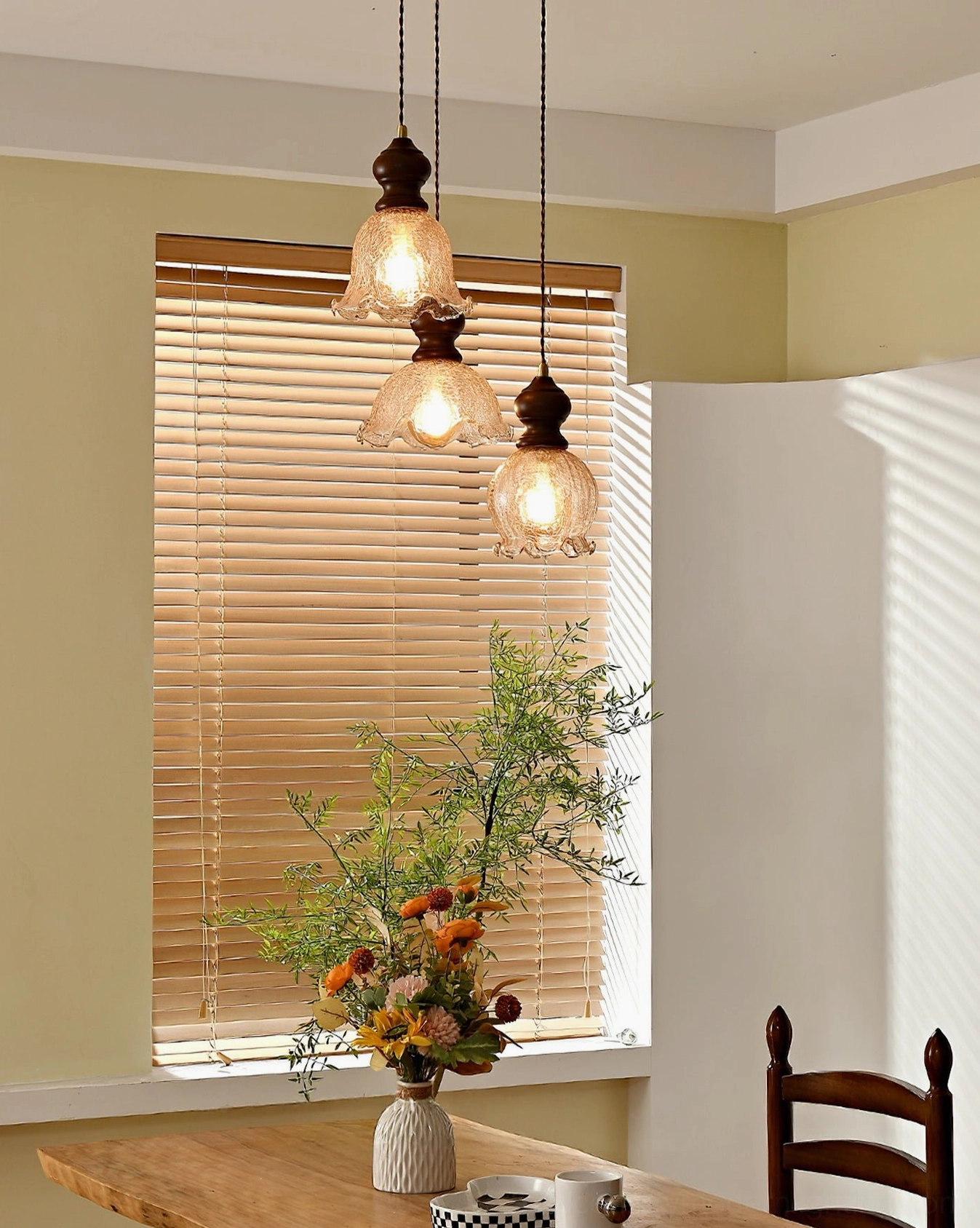Triple Barron pendant lights in dining area near sunlit window with natural light and potted flowers