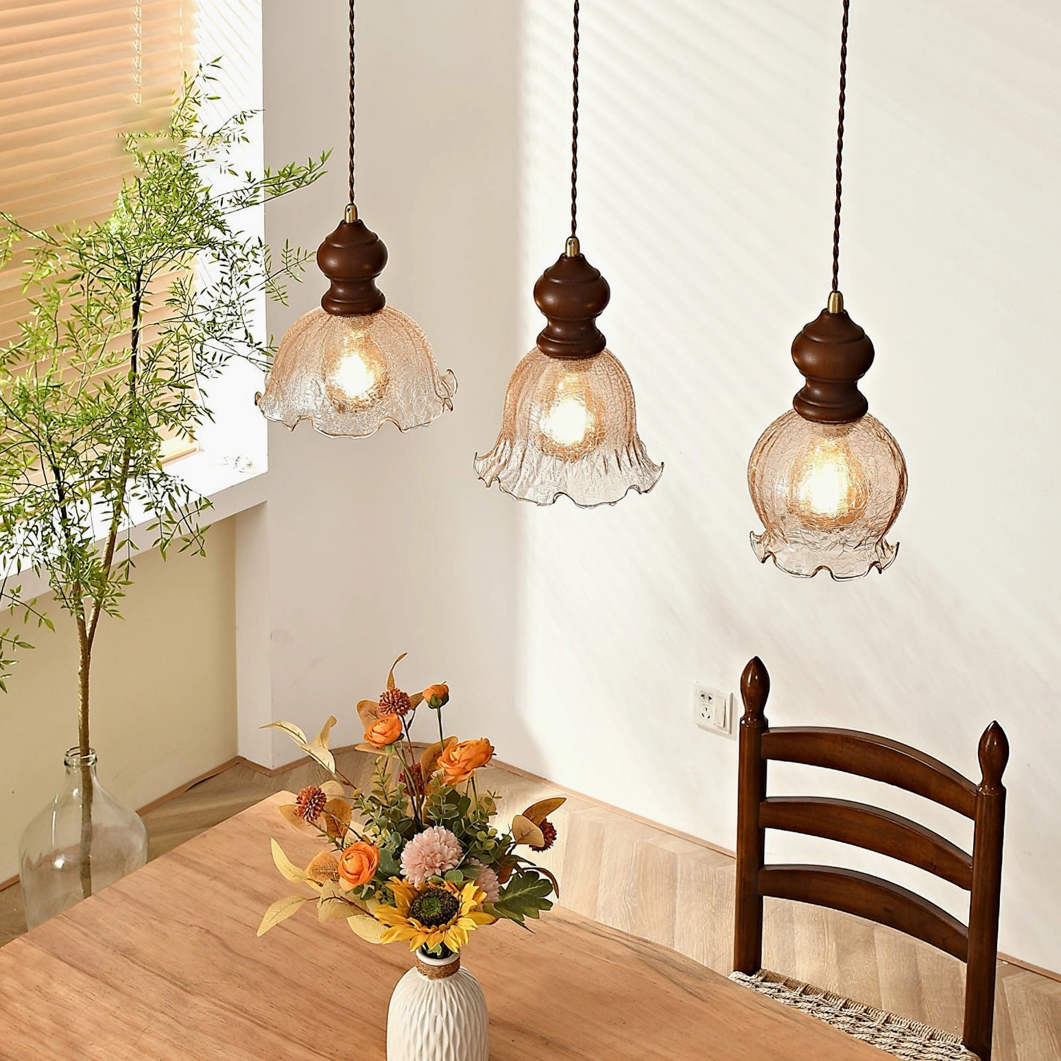 Three Barron vintage pendant lamps suspended over dining area by window with potted plant decor