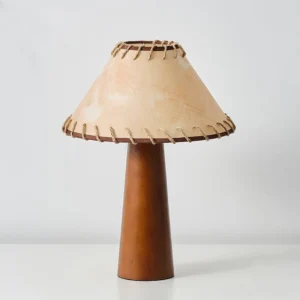 Basica table lamp showcasing tawny walnut wood base with detailed hand-stitched fabric shade trim, studio shot