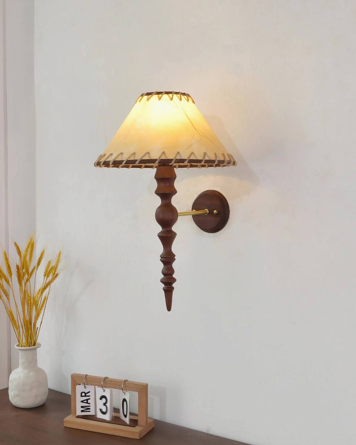 Basica wall lamp installed in bedroom bedside area with wheat vase and calendar decor