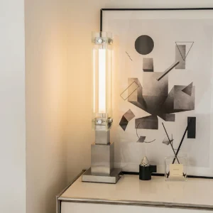 Contemporary table lamp with integrated LED glowing warmly on vanity desk with abstract wall art