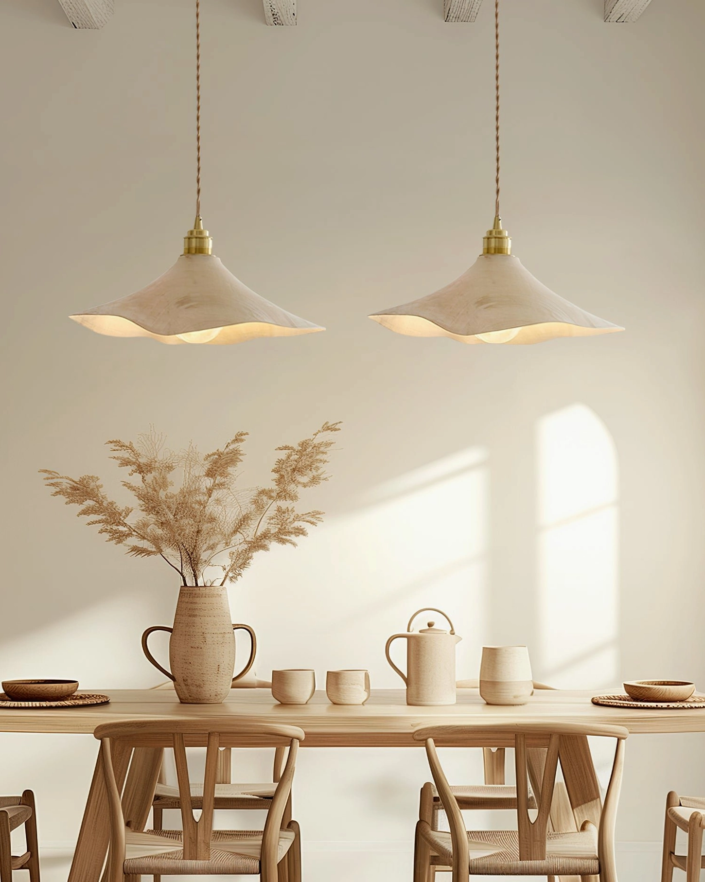 Two matching Baxter pendant lights suspended above minimalist dining area with dried floral table decor and neutral aesthetics