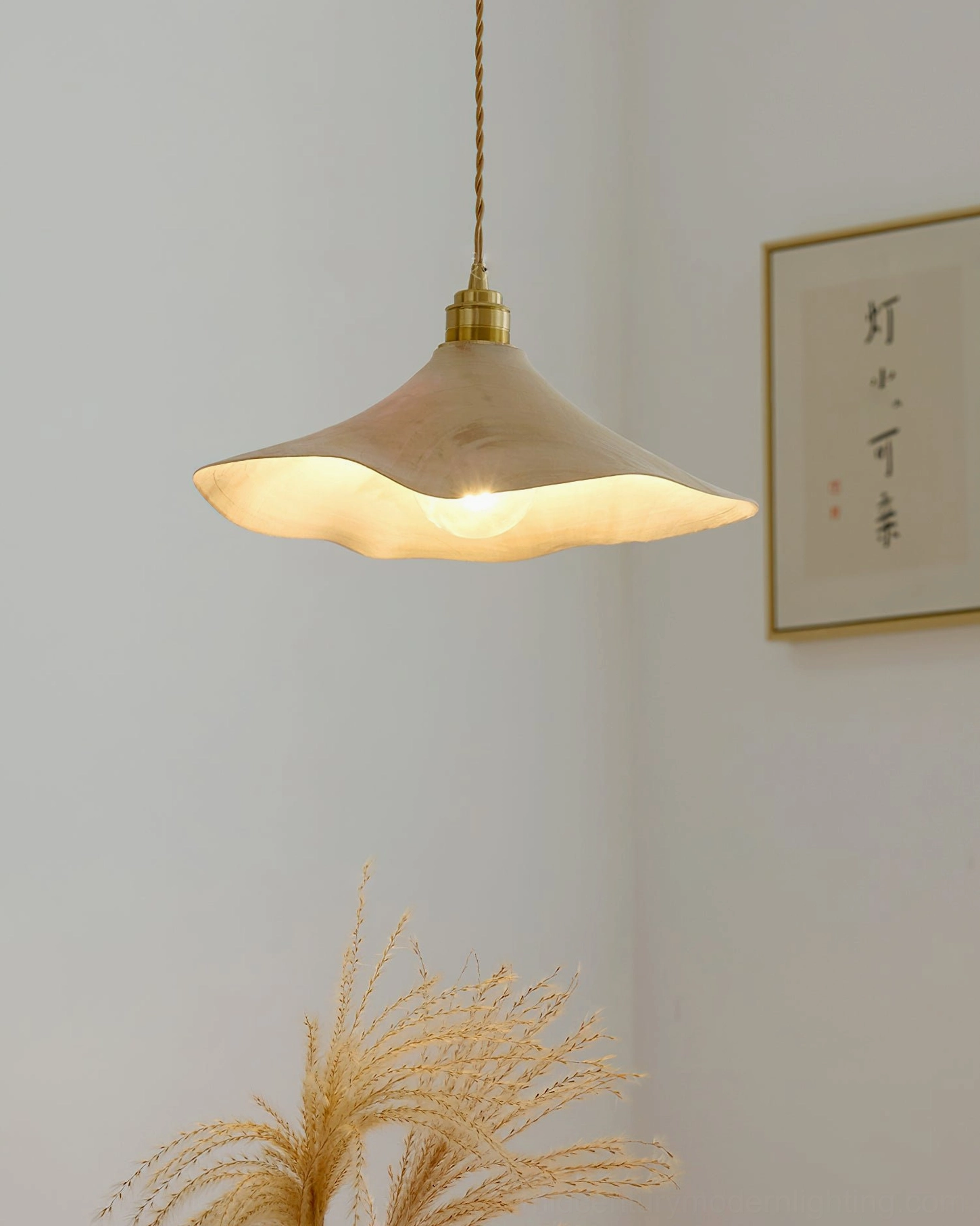 Baxter wabi-sabi pendant light with warm glow in minimalist space with Japanese calligraphy wall art in background