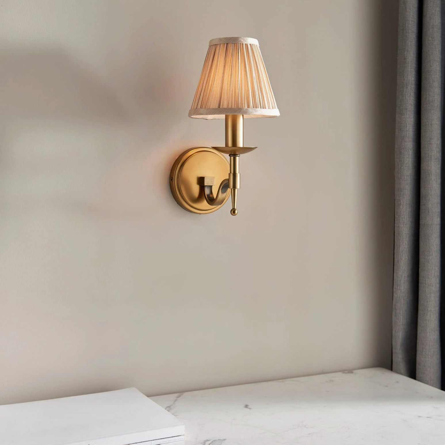 Compact Baylor single-arm brass wall sconce installed in home interior with neutral walls and marble accents