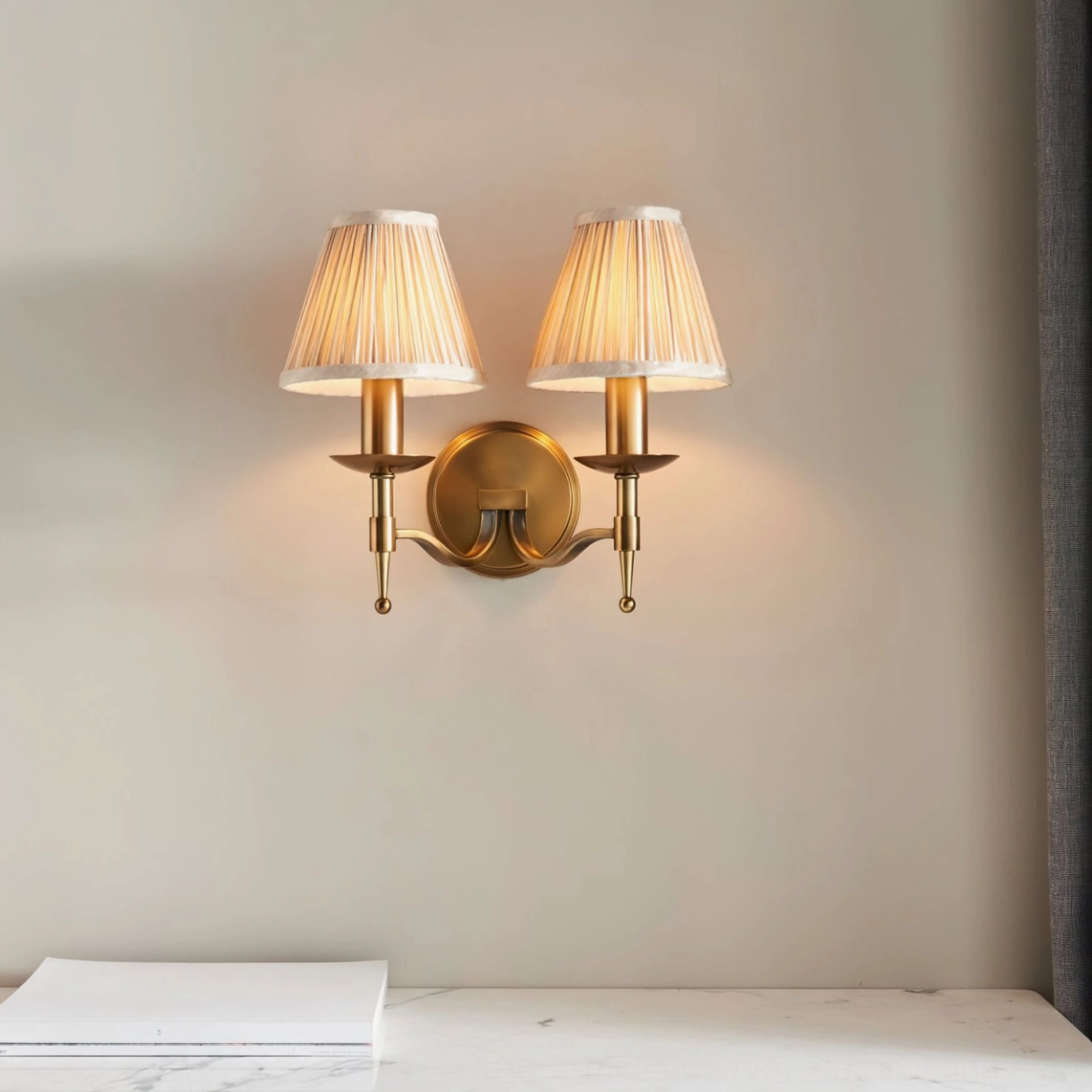 Pair of Baylor brass wall sconces with double arms symmetrically mounted on minimalist home interior wall
