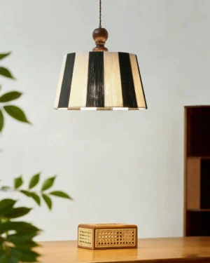 Beatrice pendant light illuminated above wooden dining table in mid-century modern dining room with rattan decor and green plants