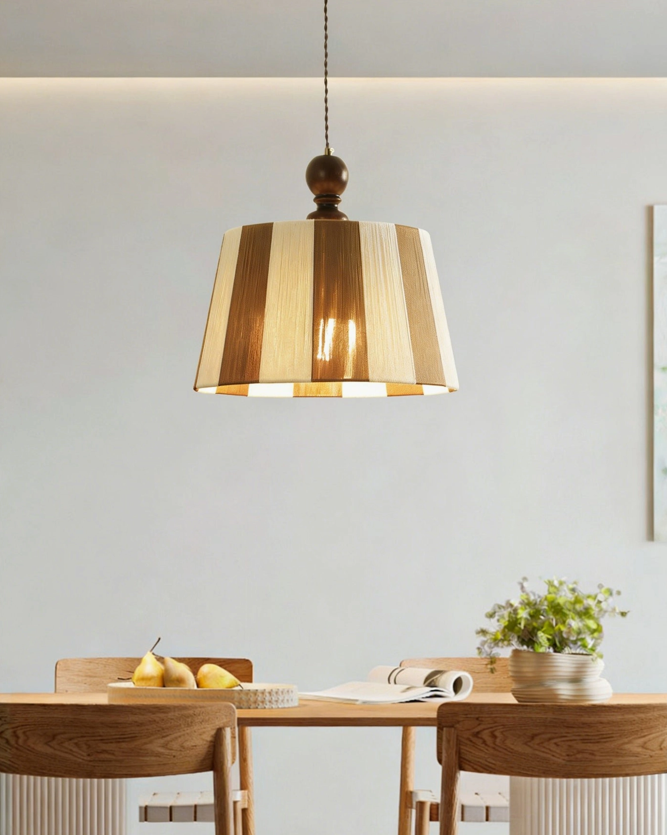 Beatrice neutral stripe pendant lamp hanging above long wooden dining table in minimalist dining space with potted plant
