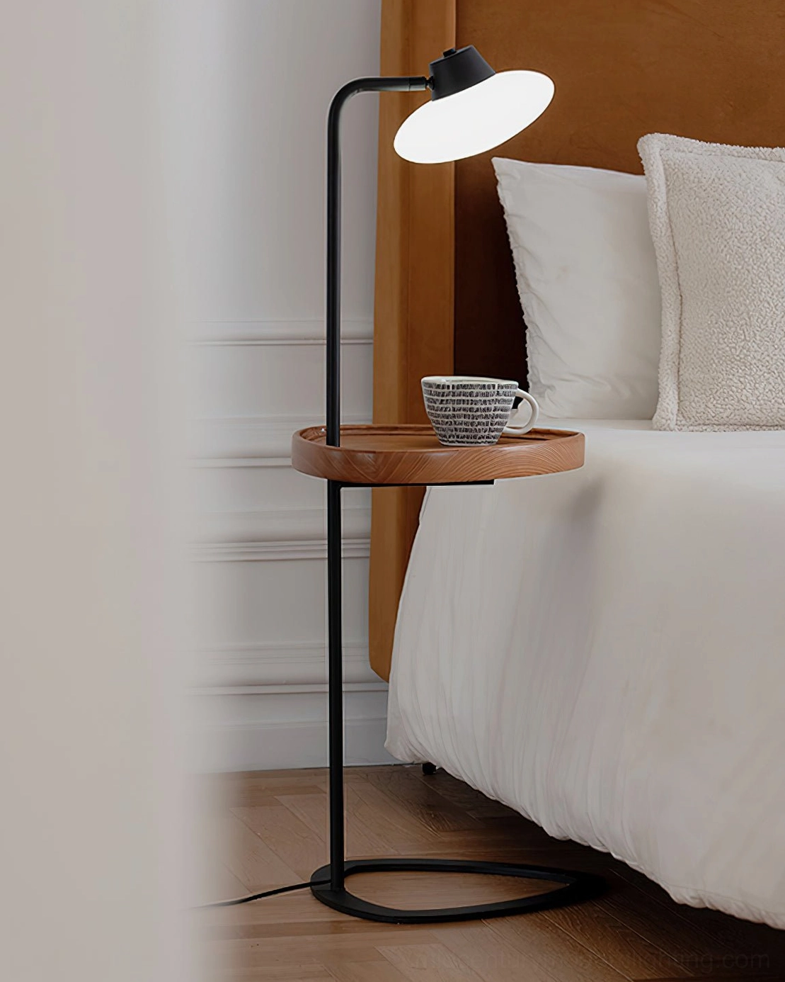 Beatrix floor lamp creating warm ambient light beside cozy bed with white linens, mid-century bedroom lighting