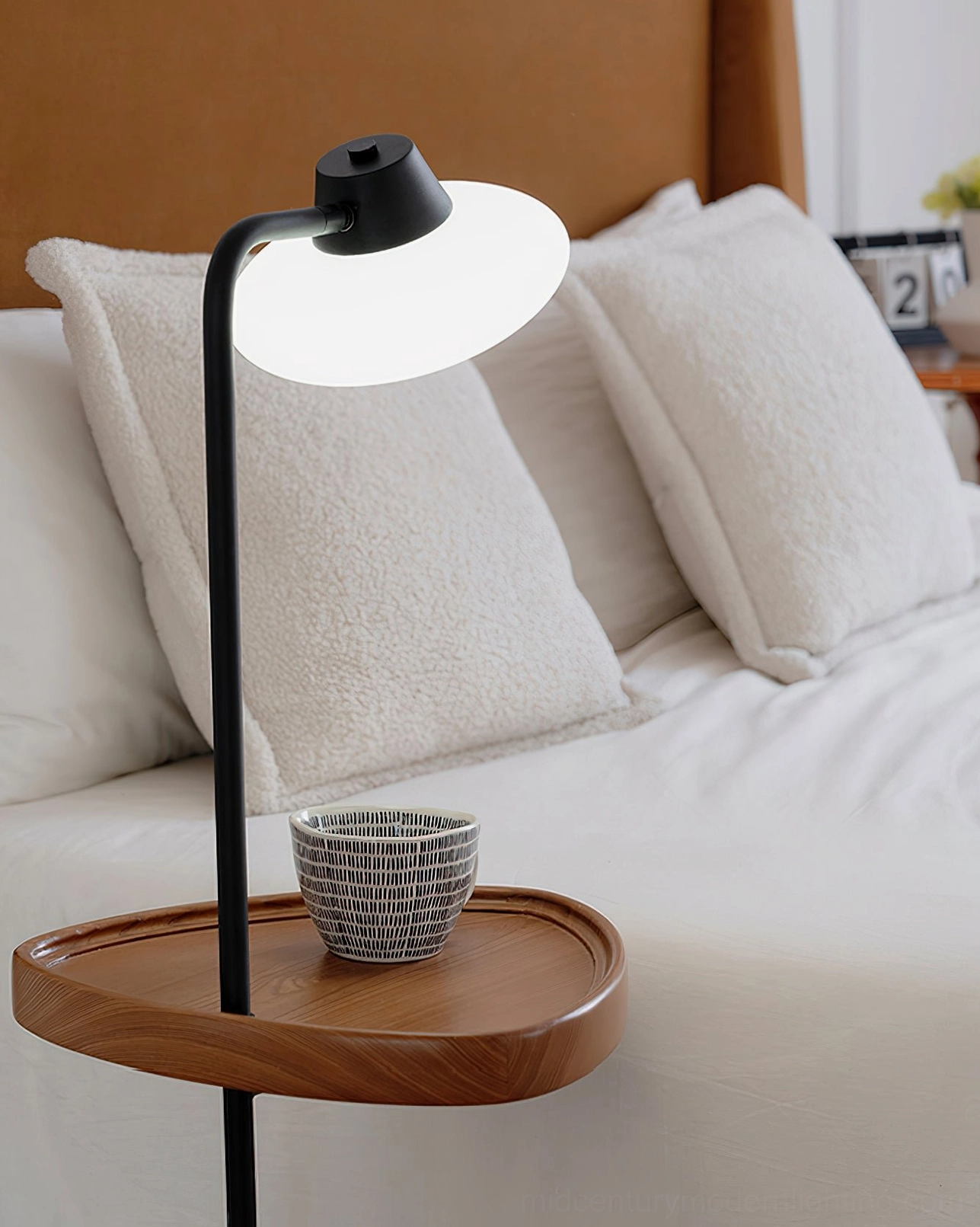 Close-up detail of Beatrix floor lamp shade and wooden tray beside plush bed pillows, quality craftsmanship