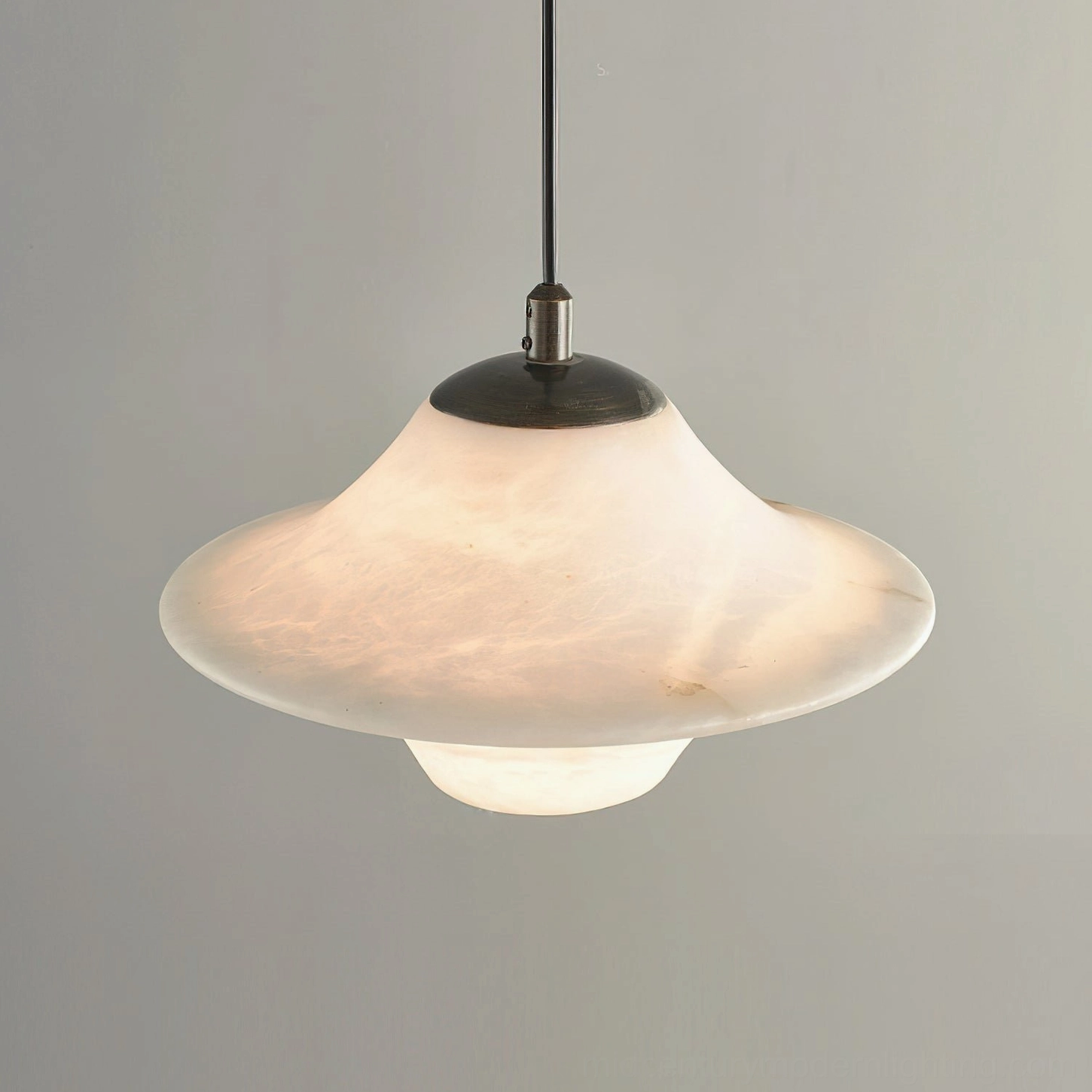 Close-up of Beckett alabaster pendant light showing dark bronze hardware detail and smooth stone shade finish