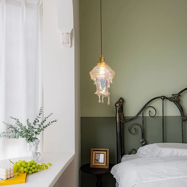 Warm-lit resin pendant lamp hanging above bedroom side table in vintage home interior