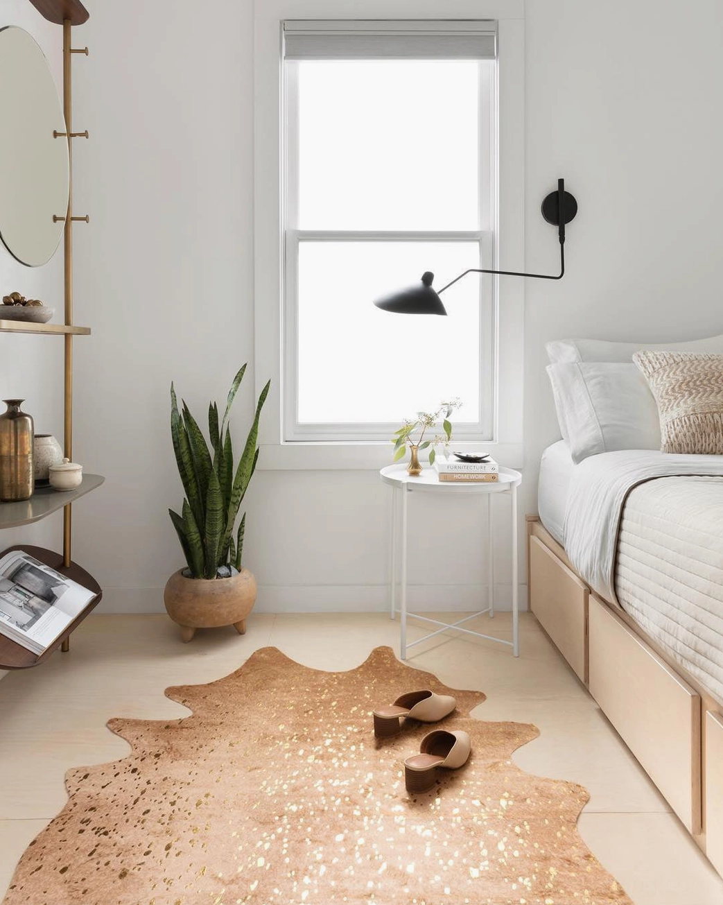 Single-arm swing arm sconce in matte black installed above bed in minimalist bedroom interior
