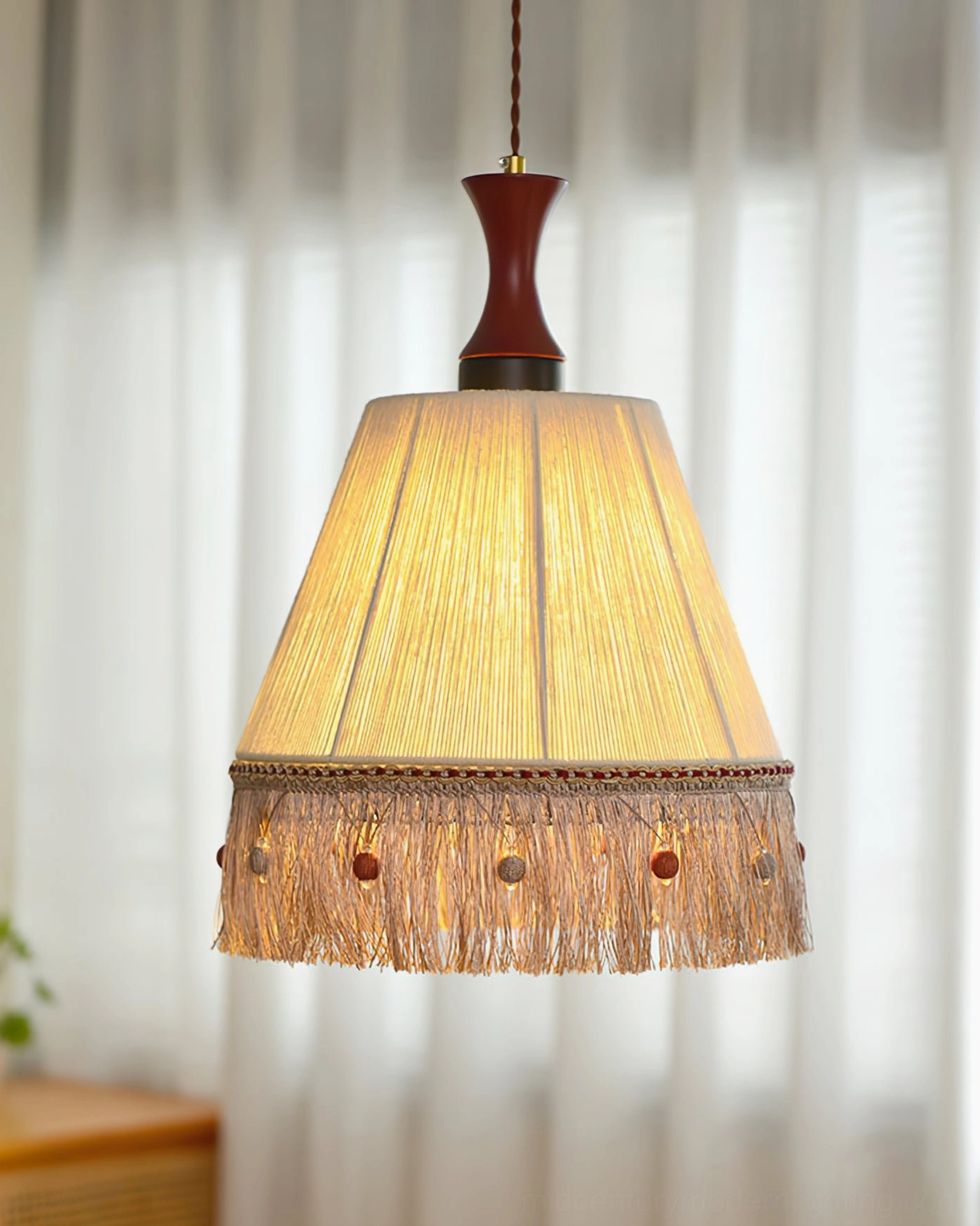 Illuminated beige cotton fringe pendant lamp with complete tassel and bead trim in living space