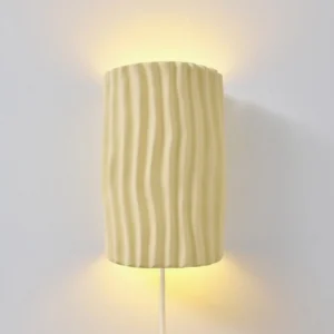 Close-up of beige pleated resin sconce shade with warm G9 LED light, wall-mounted detail shot