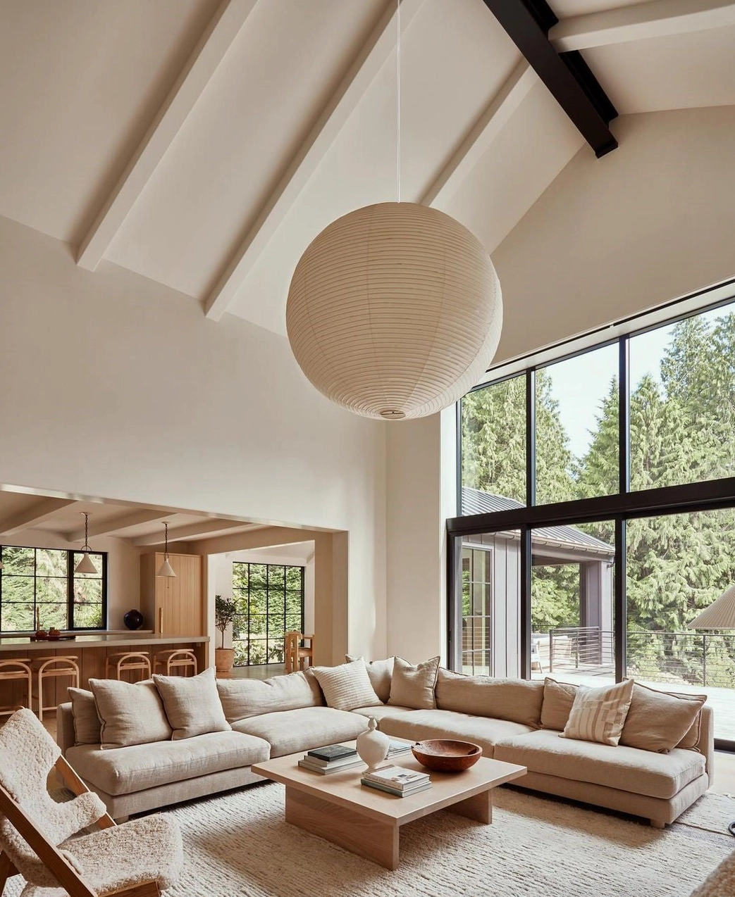 Beige washi paper sphere pendant light in bright modern villa living room with large windows, wabi-sabi minimalist interior