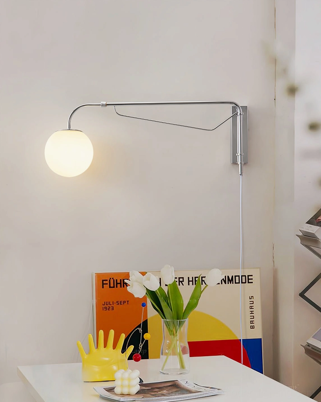 Rotating wall sconce with adjustable arm illuminating table display and floral arrangement