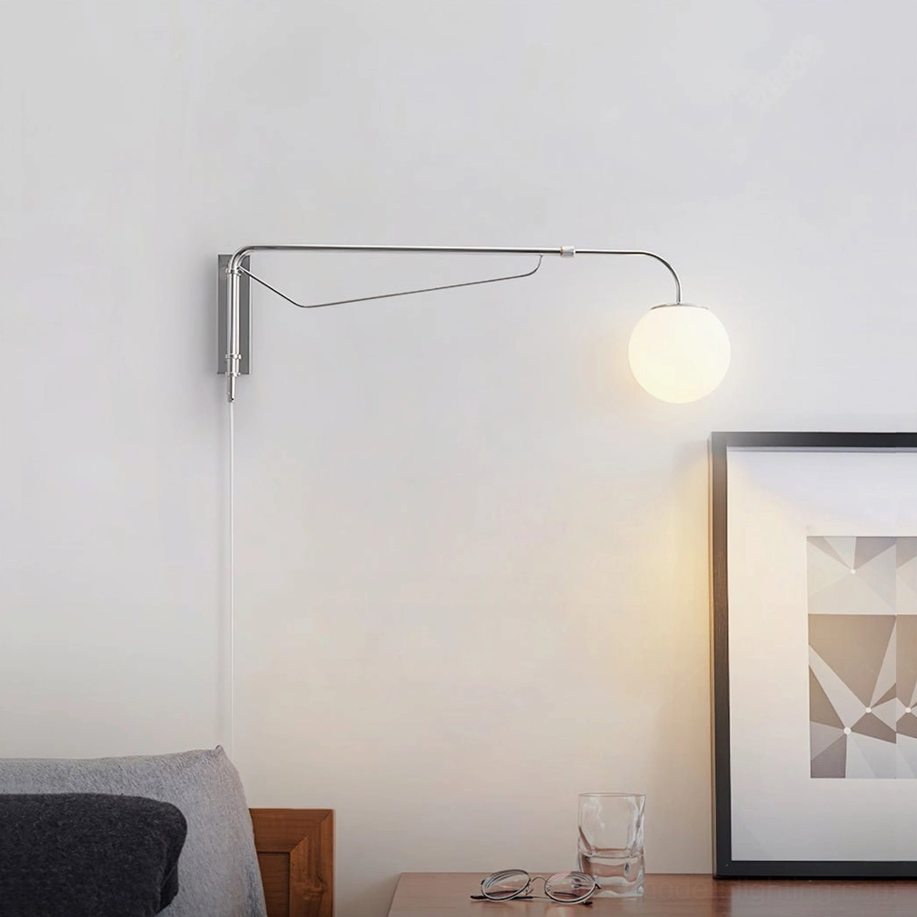 Modern chrome swing arm wall lamp in contemporary living room with sofa, creating warm accent lighting