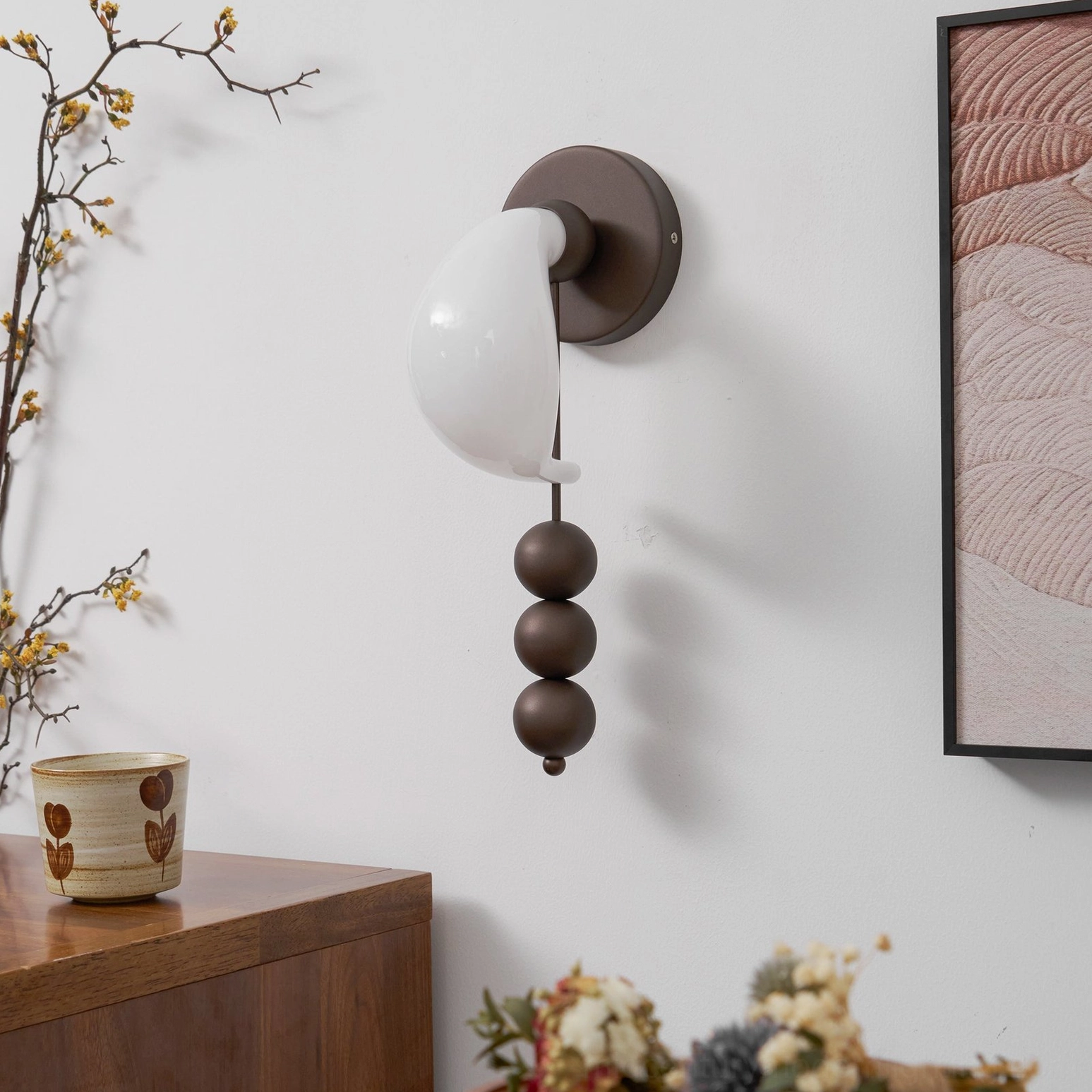 Sculptural bent glass wall sconce with curved shade and brass metal framework, side angle view near wooden side table