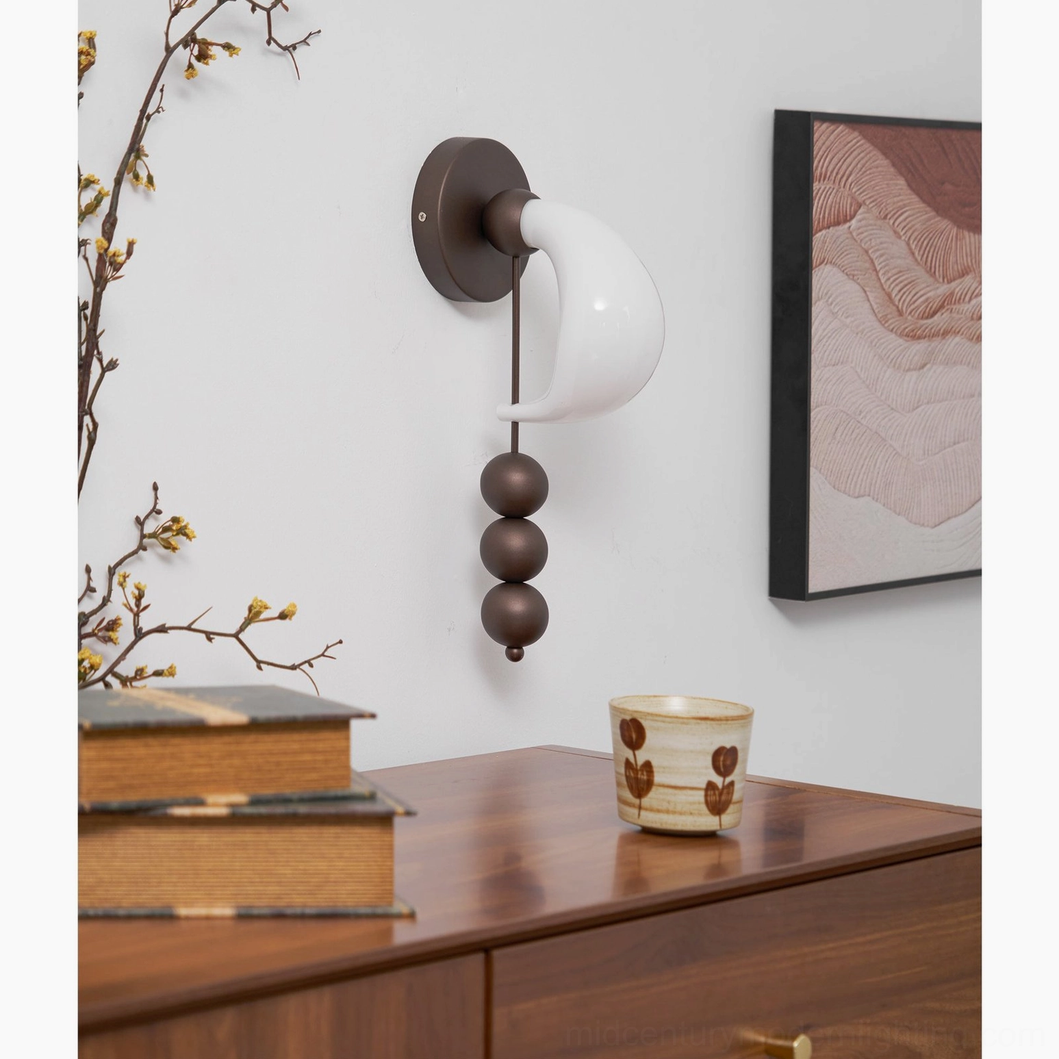 Mid-century modern bent glass wall sconce installed in home study nook with wooden dresser, showing warm ambient lighting and architectural presence