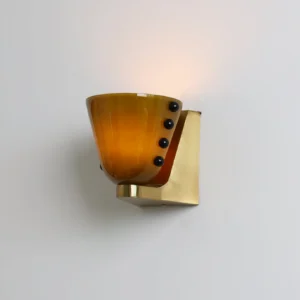 Illuminated Berries wall lamp with amber glass casting warm glow, brass base and light fixtures, eye-level perspective