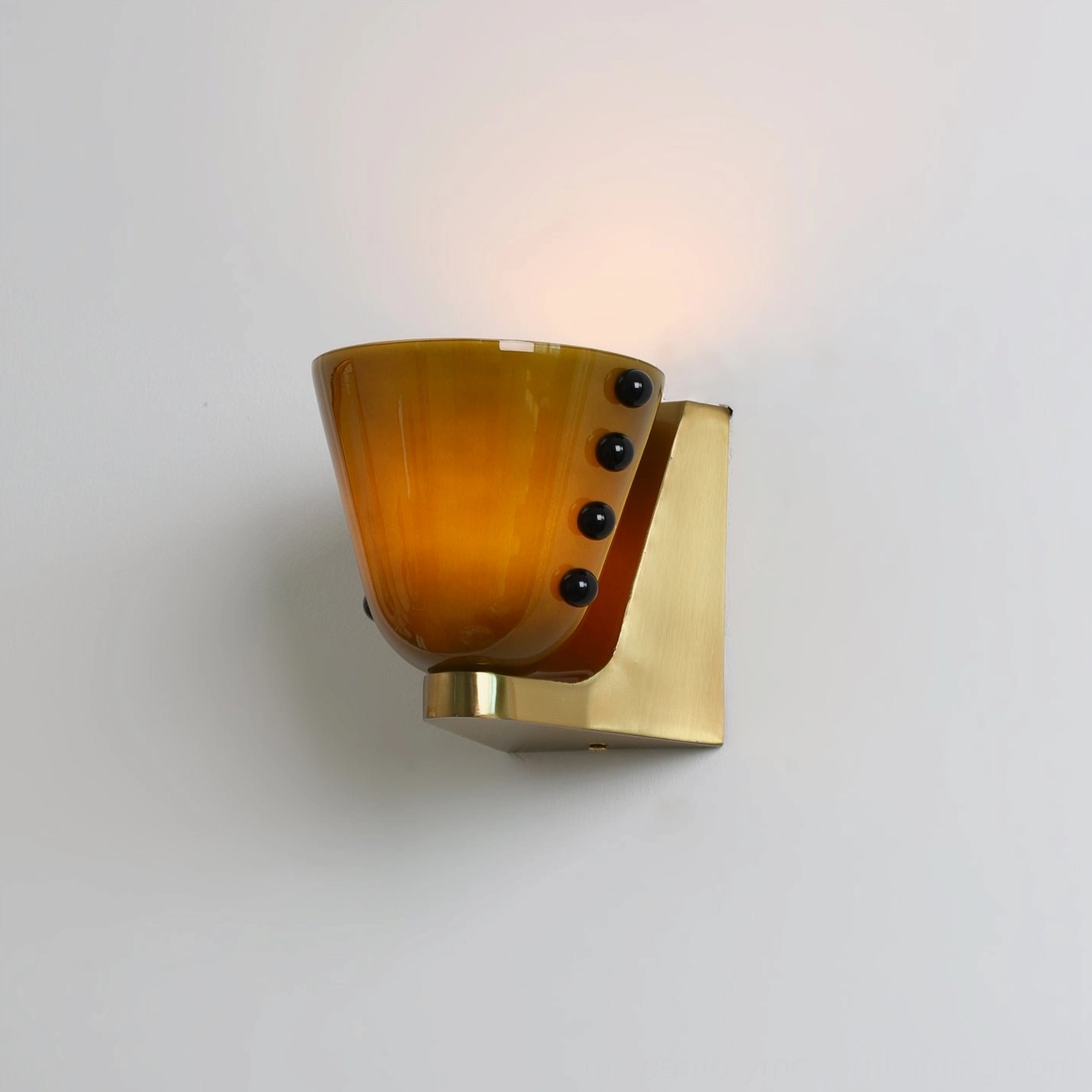 Illuminated Berries wall lamp with amber glass casting warm glow, brass base and light fixtures, eye-level perspective