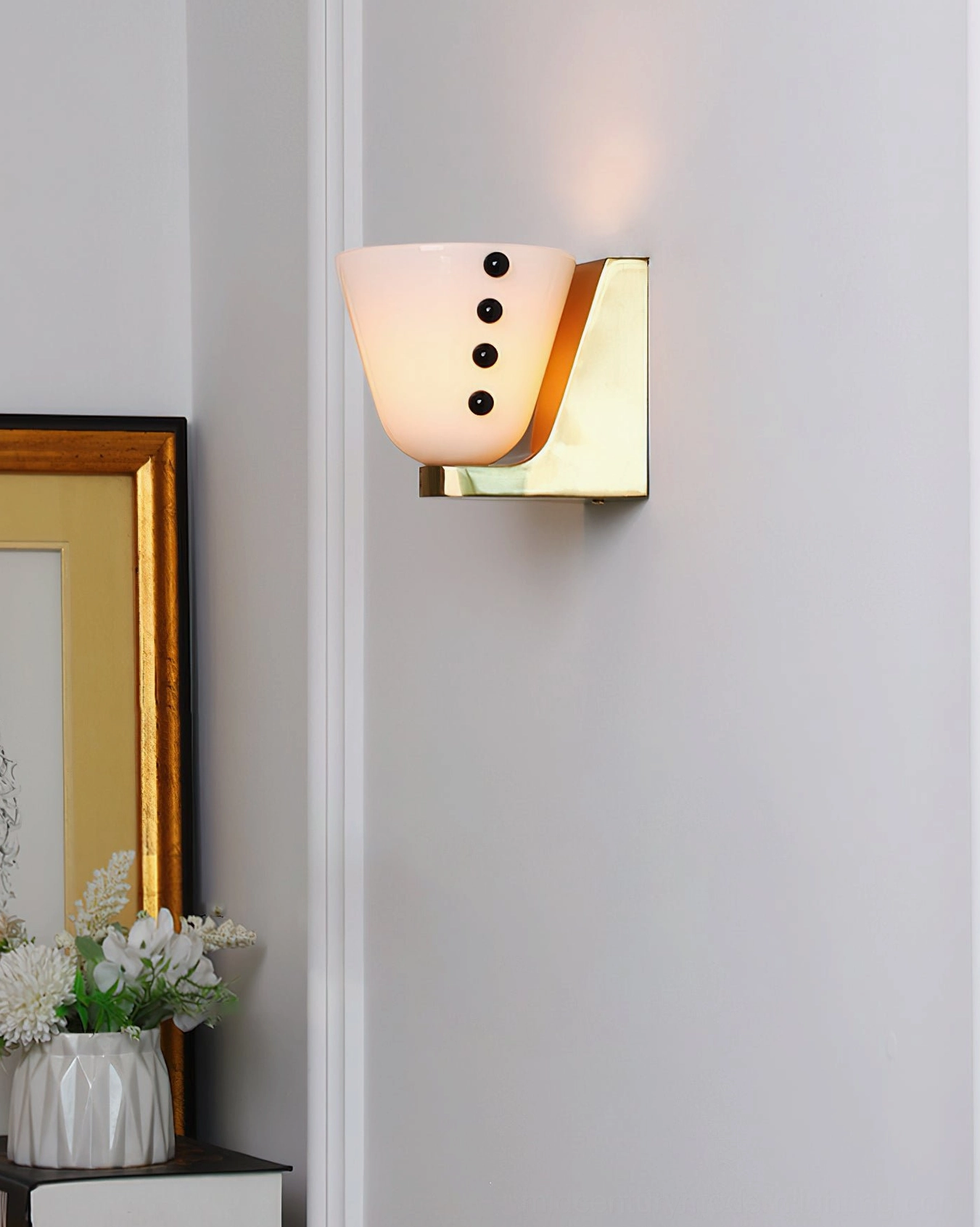 Illuminated Berries wall sconce with milky white frosted glass creating warm ambient glow in hallway setting with framed artwork